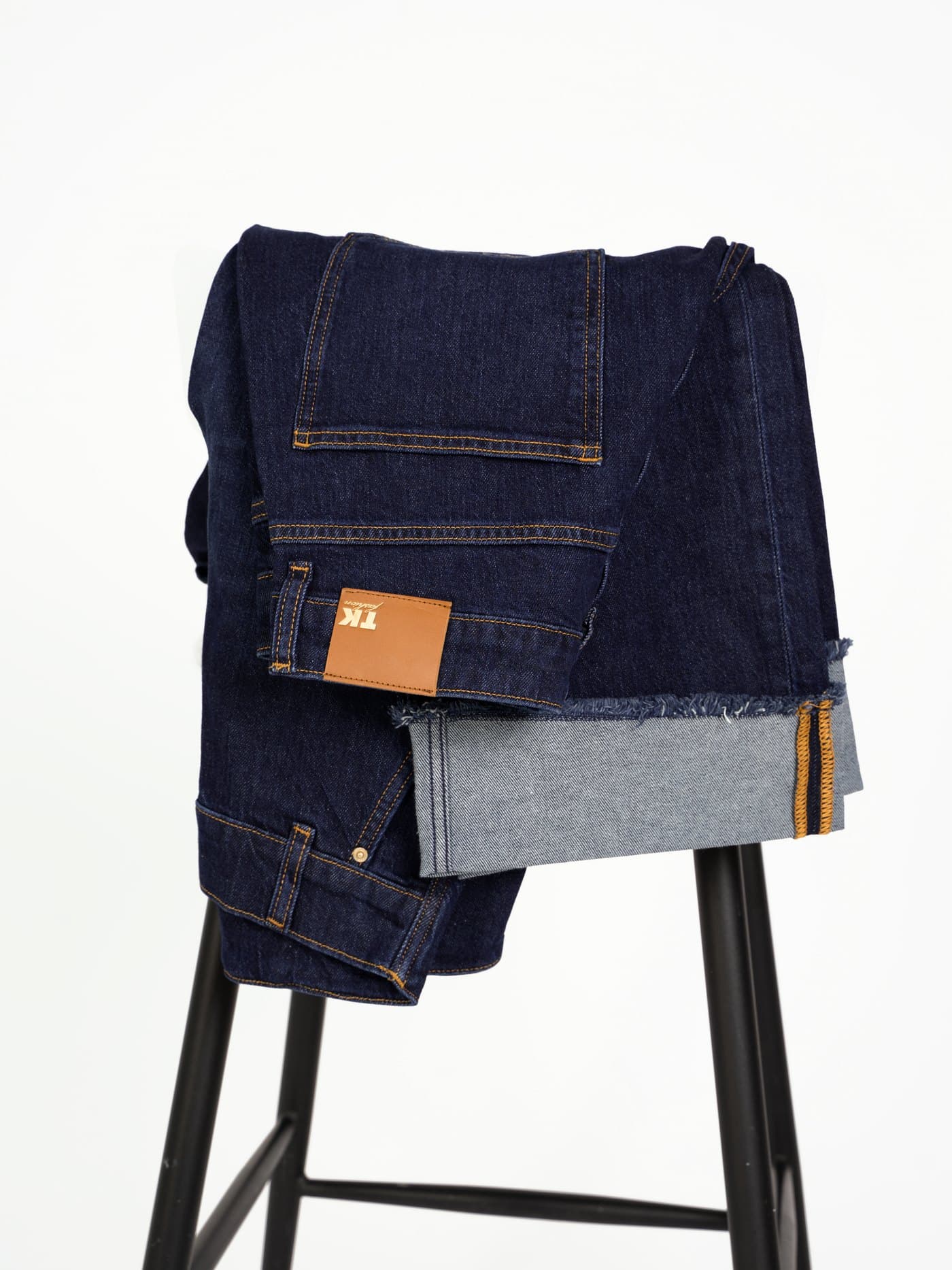TK Fashion — folded jeans with leather brand patch and raw hem